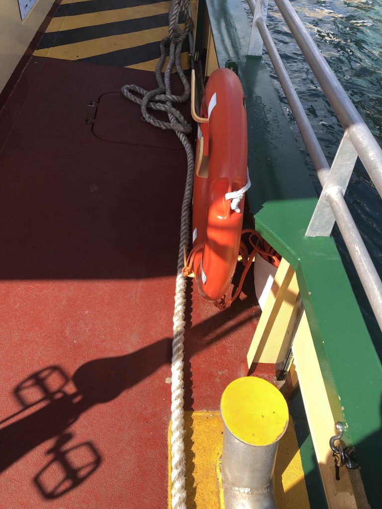 A detail photo of a ferry deck with painted fitting in red, green and yellow. strong shadows and sunlight.